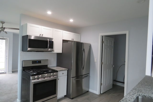 kitchen with light stone countertops, ceiling fan, stainless steel appliances, decorative backsplash, and white cabinets