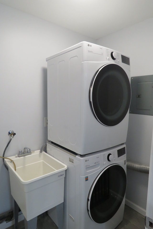 laundry room featuring electric panel, sink, and stacked washer / drying machine