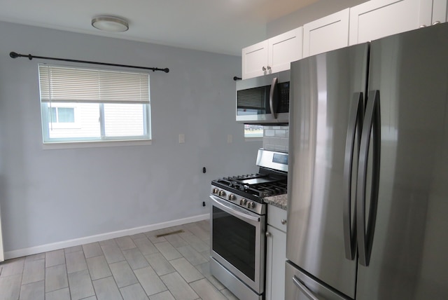 kitchen with light stone countertops, white cabinets, and appliances with stainless steel finishes