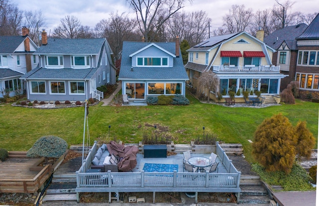 back of property with an outdoor hangout area, a balcony, a lawn, and a wooden deck