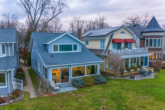 back of property with a lawn, solar panels, and a balcony