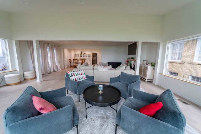 living room featuring light wood-type flooring, a high ceiling, and a wealth of natural light