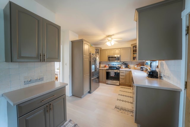 kitchen featuring sink, ceiling fan, appliances with stainless steel finishes, gray cabinetry, and decorative backsplash