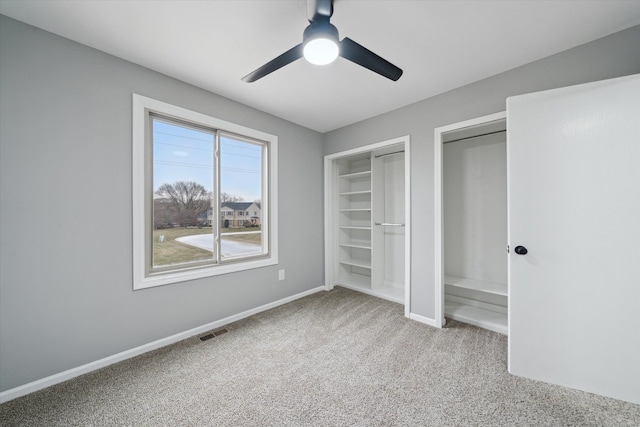 unfurnished bedroom with multiple closets, light colored carpet, and ceiling fan