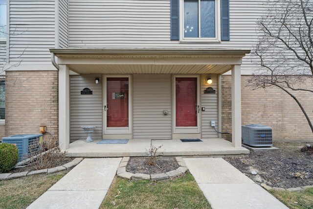 view of exterior entry with central air condition unit and a porch