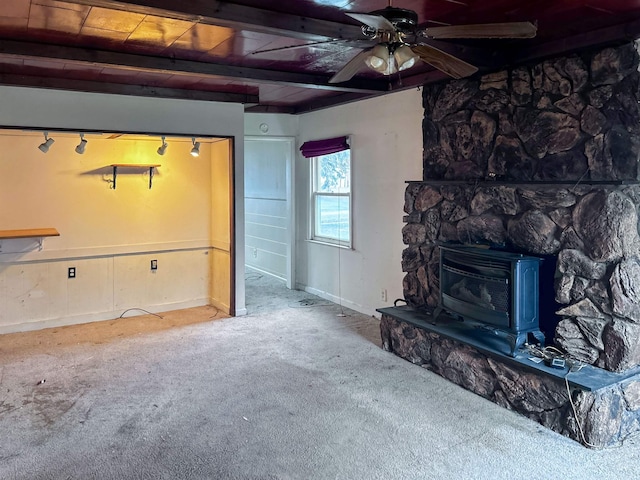 carpeted living room with beam ceiling, a wood stove, ceiling fan, and wood ceiling