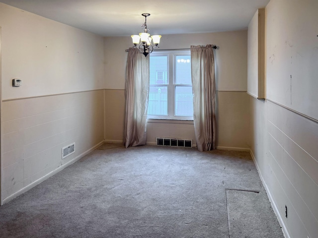 carpeted empty room featuring a notable chandelier