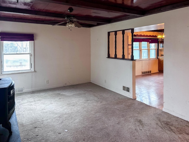 carpeted spare room with beamed ceiling, ceiling fan with notable chandelier, and a wealth of natural light