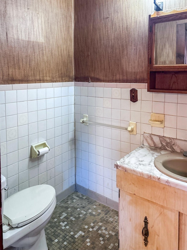 bathroom featuring tile patterned floors, vanity, toilet, and tile walls