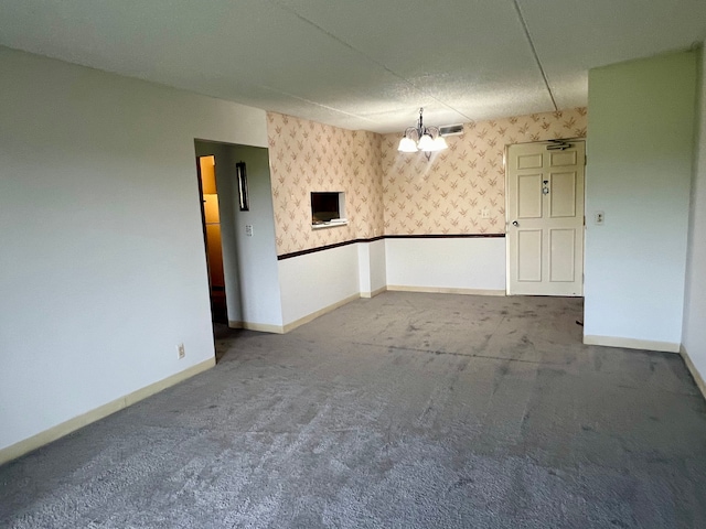 carpeted empty room with a textured ceiling and a chandelier