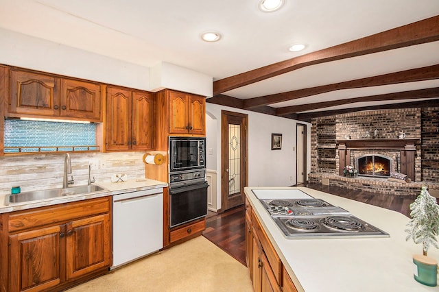 kitchen featuring beamed ceiling, sink, a brick fireplace, and black appliances