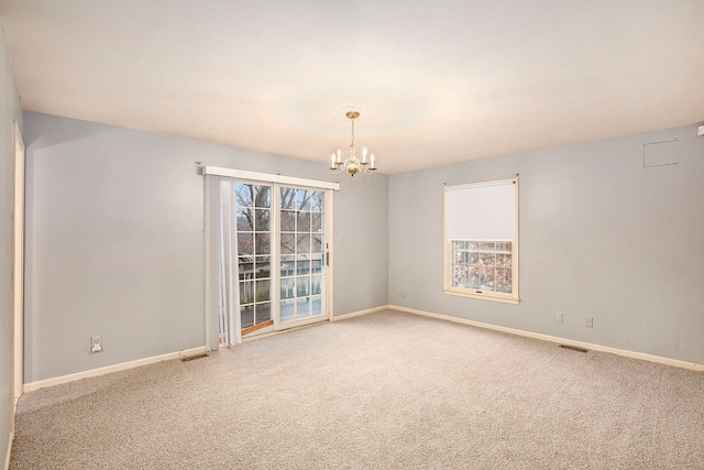 carpeted empty room with a chandelier