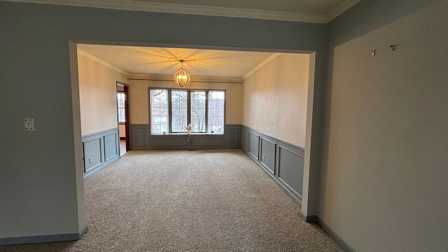 carpeted empty room featuring an inviting chandelier and ornamental molding