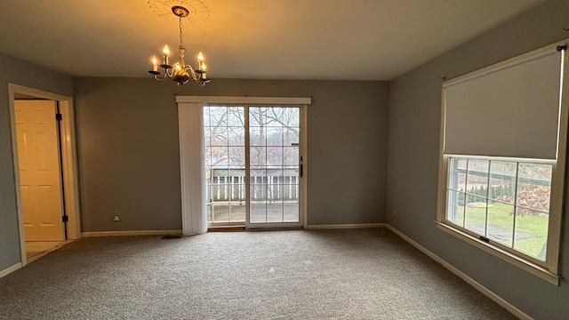 spare room with carpet flooring and an inviting chandelier