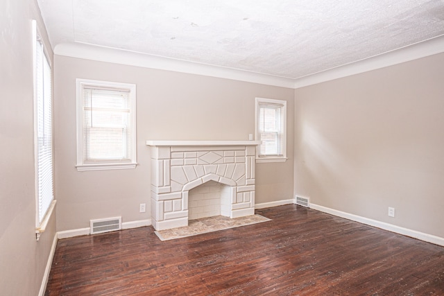 unfurnished living room featuring a textured ceiling, dark hardwood / wood-style flooring, and ornamental molding