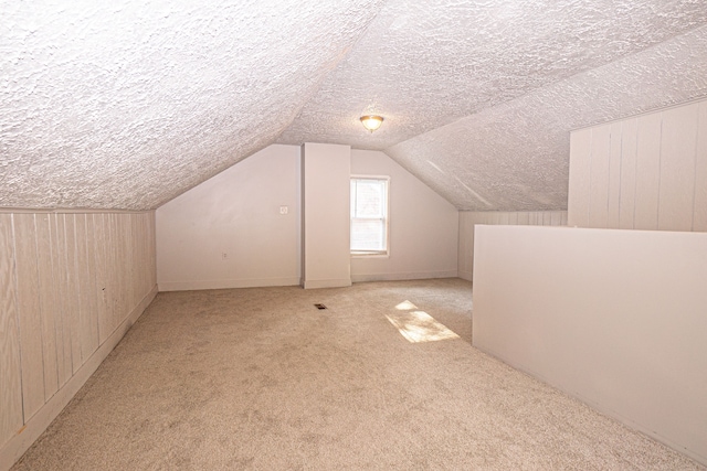 bonus room featuring vaulted ceiling, light carpet, and a textured ceiling