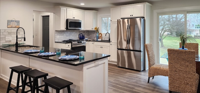 kitchen with white cabinets, appliances with stainless steel finishes, wood-type flooring, and sink