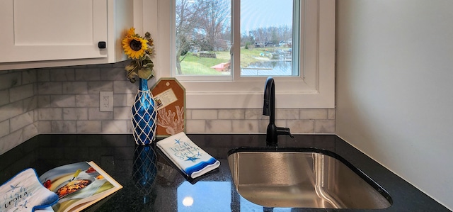 room details featuring backsplash, sink, and white cabinets