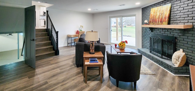 living room featuring wood-type flooring and a brick fireplace