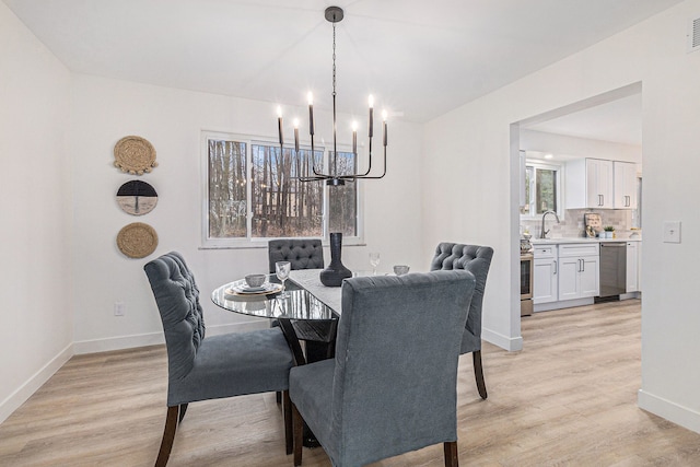 dining area featuring sink, a chandelier, and light wood-type flooring