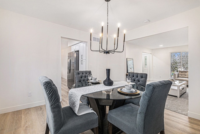 dining area featuring light wood-type flooring and an inviting chandelier