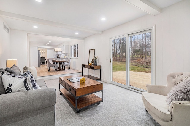 living room with light carpet, beamed ceiling, and a notable chandelier