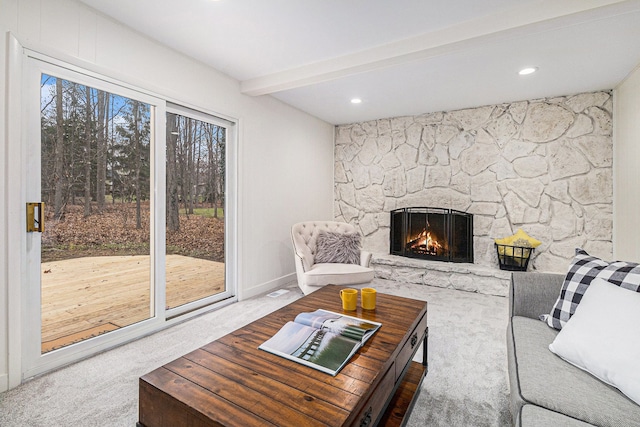 carpeted living room featuring beamed ceiling and a fireplace