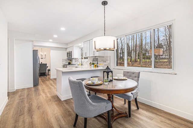 dining space with light wood-type flooring and sink