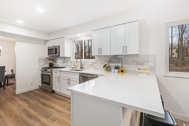 kitchen featuring sink, kitchen peninsula, a healthy amount of sunlight, white cabinetry, and stainless steel appliances