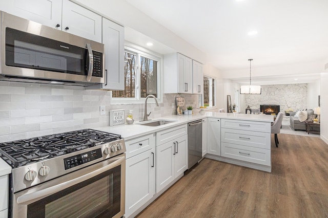 kitchen featuring kitchen peninsula, stainless steel appliances, sink, white cabinets, and dark hardwood / wood-style floors