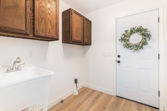 laundry room with cabinets, light hardwood / wood-style flooring, and sink