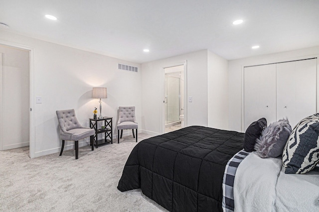 bedroom with light carpet, ensuite bath, and a closet