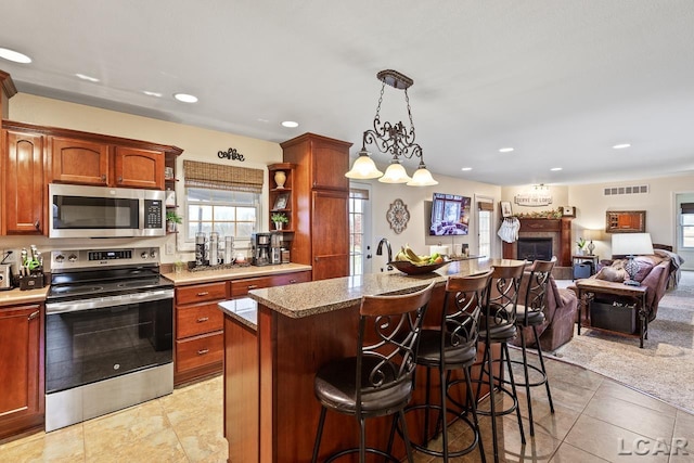 kitchen featuring a breakfast bar, stainless steel appliances, a kitchen island, hanging light fixtures, and light tile patterned flooring