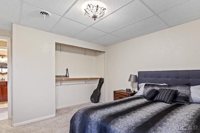 carpeted bedroom with a paneled ceiling and a closet