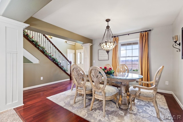 dining room with decorative columns, dark hardwood / wood-style floors, and a notable chandelier