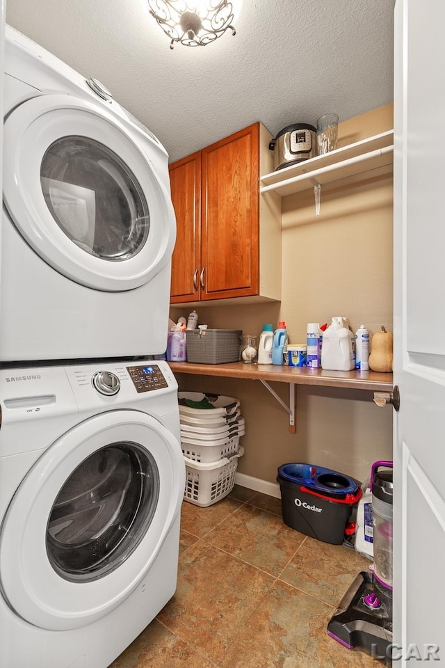 laundry area featuring stacked washer / drying machine, cabinets, and a textured ceiling