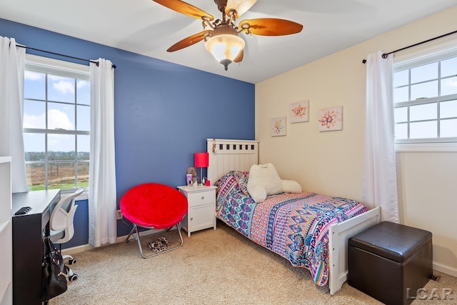 bedroom with multiple windows, ceiling fan, and light colored carpet