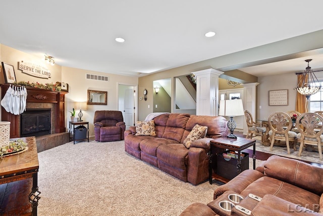 carpeted living room with a fireplace and an inviting chandelier