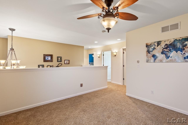 carpeted empty room featuring ceiling fan with notable chandelier