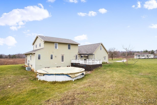 rear view of house featuring a lawn, central air condition unit, and a swimming pool side deck