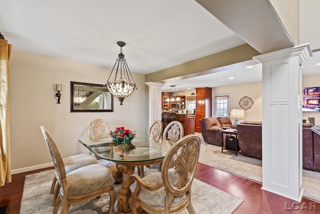 dining room featuring ornate columns and dark wood-type flooring