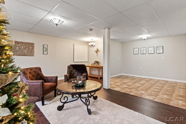 sitting room with wood-type flooring, a paneled ceiling, and a notable chandelier