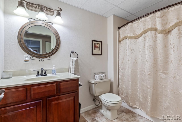 bathroom with curtained shower, a drop ceiling, tile patterned flooring, toilet, and vanity