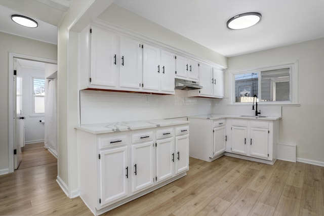 kitchen with light hardwood / wood-style floors, white cabinetry, and sink