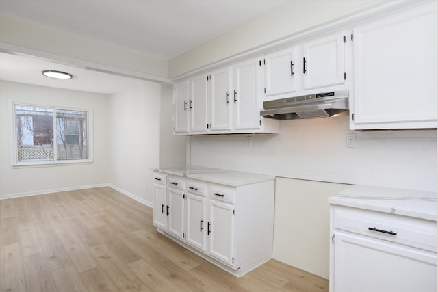 kitchen featuring decorative backsplash, light stone countertops, white cabinetry, and light hardwood / wood-style flooring