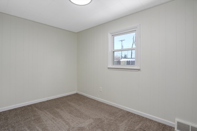 unfurnished room featuring carpet flooring and wooden walls