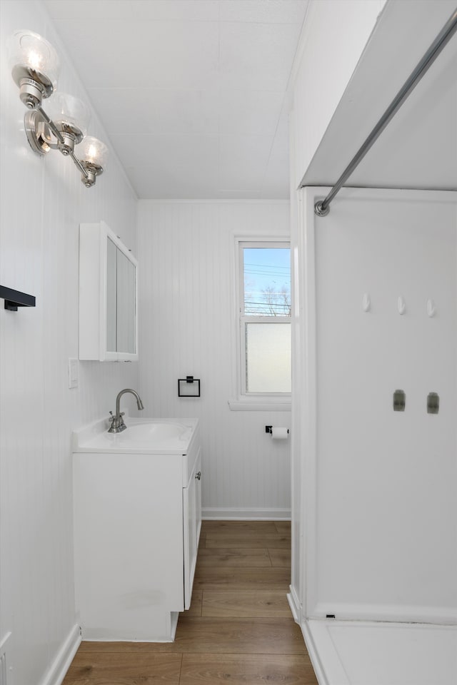 bathroom with wood walls, hardwood / wood-style floors, and vanity