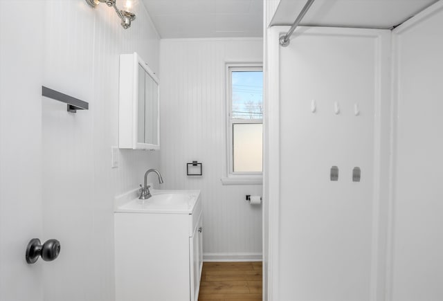 bathroom with hardwood / wood-style floors, vanity, and wood walls