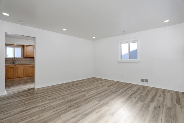 unfurnished room featuring a healthy amount of sunlight, light wood-type flooring, and sink