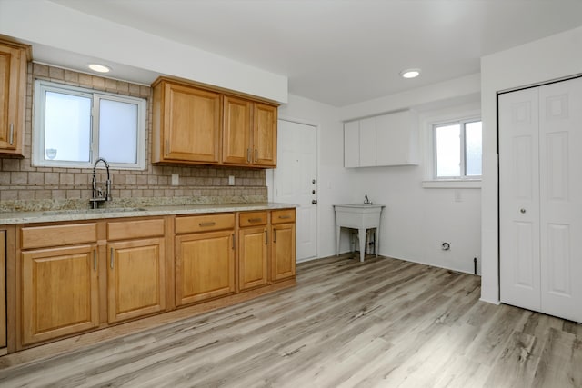 kitchen featuring decorative backsplash, sink, light stone countertops, and light wood-type flooring